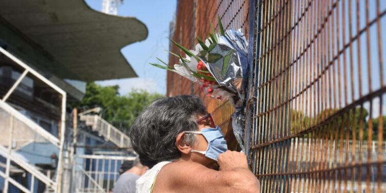 Una mujer deja sus flores en el alambrado al lado de la Techada