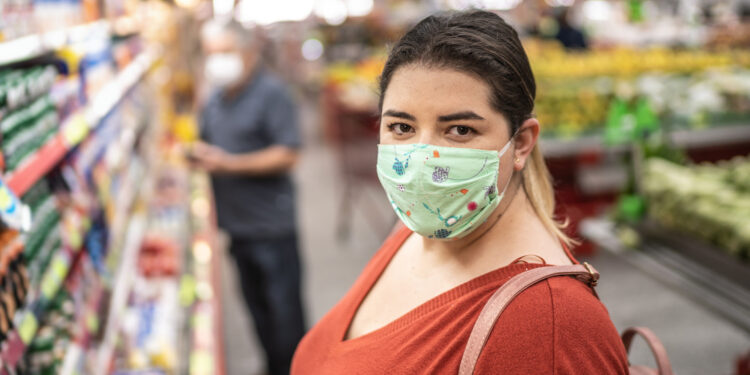 Portrait of woman with disposable medical mask shopping in supermarket