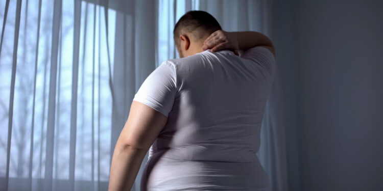 Obese man stretching neck muscles, back pain problems caused by overweight